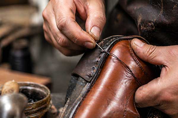 Reparación calzado Zapatería Chelu Primer plano de un zapatero cosiendo un zapato.