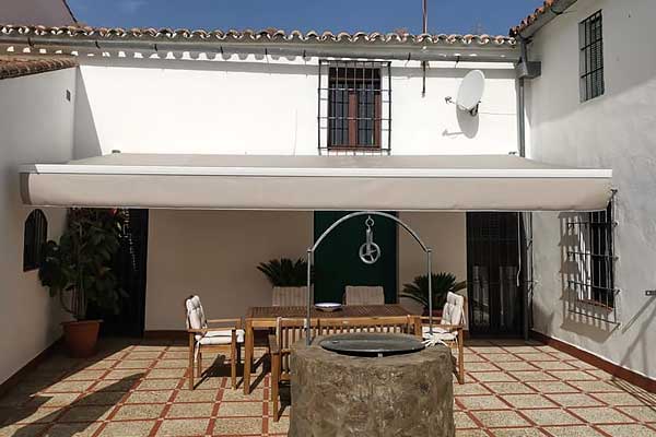 Toldos y tapizado Zapatería Chelu Toldo extensible instalado en un patio rústico.